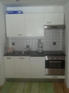 uma cozinha com armários brancos e um lavatório em Ferienwohnung Familie Tost em Trins