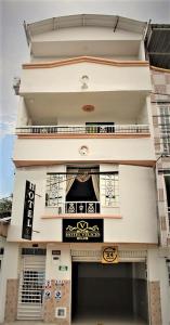 a tall white building with a sign on it at Hotel Velices in Buga