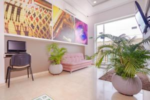 a living room with a pink couch and two potted plants at Hotel Ribera Sinu in Montería