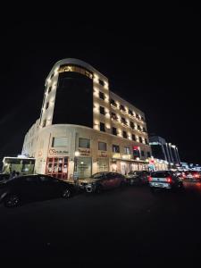 a building with cars parked in a parking lot at night at Baden Hotel Suites in Amman