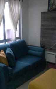 a blue couch in a living room with a window at Aptos Farroupilha in Farroupilha