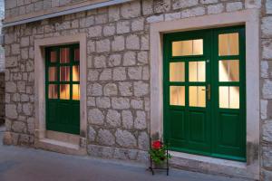 two green doors on a stone building with a flower at Apartment Joe in Split