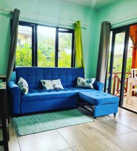 Sofá azul en la sala de estar con ventanas en Casa De Leela Self Catering Guest House, en La Digue