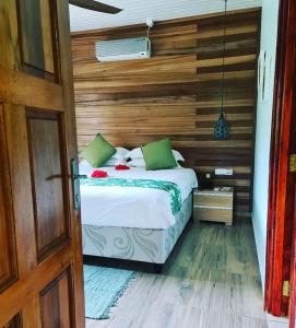 1 dormitorio con 1 cama con pared de madera en Casa De Leela Self Catering Guest House, en La Digue