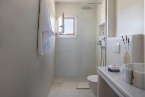 a white bathroom with a sink and a toilet at Ammothines Cycladic Suites in Naxos Chora