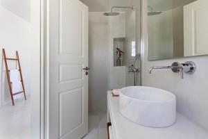 a white bathroom with a sink and a mirror at Ammothines Cycladic Suites in Naxos Chora
