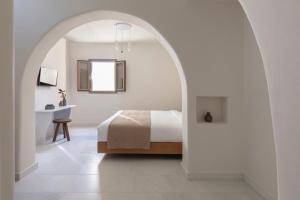a white bedroom with a bed and a desk at Ammothines Cycladic Suites in Naxos Chora