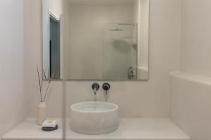 a white bathroom with a sink and a mirror at Ammothines Cycladic Suites in Naxos Chora