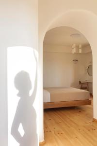 a bedroom with a bed and a shadow of a person at Ammothines Cycladic Suites in Naxos Chora