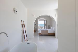 a white bedroom with a bed and a view of the ocean at Ammothines Cycladic Suites in Naxos Chora +37 photos