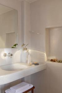 a white bathroom with a sink and a mirror at Ammothines Cycladic Suites in Naxos Chora