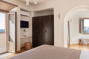 a bedroom with a bed and a wooden door at Ammothines Cycladic Suites in Naxos Chora