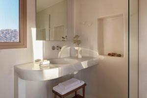 a white bathroom with a sink and a mirror at Ammothines Cycladic Suites in Naxos Chora