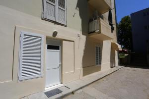 un edificio con puertas y ventanas blancas y balcón en Zadar Street Apartments and Room, en Zadar