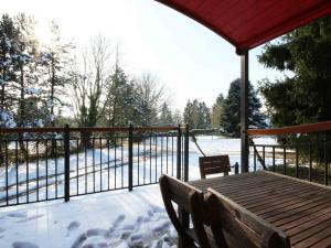 a porch with a wooden table and a fence with snow at Gîte Radon, 2 pièces, 3 personnes - FR-1-497-130 in Radon