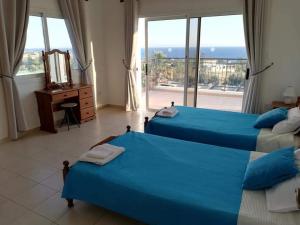 two beds in a bedroom with a view of the ocean at Gabriella in Peyia
