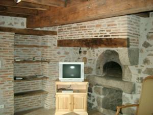 a living room with a tv and a brick fireplace at Gîte Le Crozet, 5 pièces, 12 personnes - FR-1-496-100 in Le Crozet