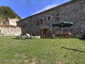 a stone building with two chairs and an umbrella at Gîte Burdignes, 4 pièces, 6 personnes - FR-1-496-96 in Burdignes