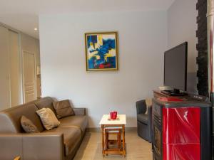 ein Wohnzimmer mit einem Sofa und einem TV in der Unterkunft Gîte Champcevinel, 4 pièces, 5 personnes - FR-1-616-99 in Champcevinel