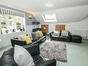 una sala de estar con muebles de cuero negro y almohadas amarillas. en 1 The Old Coach House, en Dartmouth