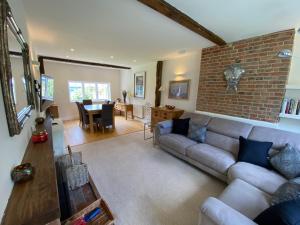 a living room with a couch and a brick wall at Amazing cottage right in the heart of Ewhurst Green, overlooking Bodiam Castle in Sandhurst