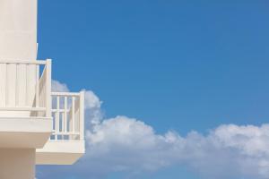 a white balcony on the side of a building with clouds at Ammothines Cycladic Suites in Naxos Chora