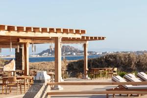 a wooden pavilion with chairs and tables and the ocean at Ammothines Cycladic Suites in Naxos Chora