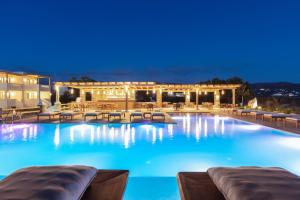 a large swimming pool with blue water at night at Ammothines Cycladic Suites in Naxos Chora