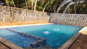a swimming pool with a waterfall in a backyard at Pavisha Farm House Swimming Pool in Pondicherry