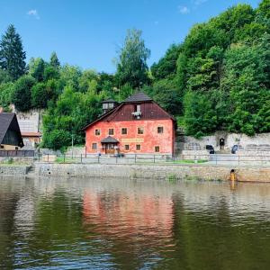 a large red brick building next to a body of water at Penzion Kapr in Český Krumlov
