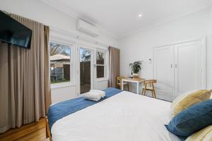 Un dormitorio con una gran cama blanca y una ventana en Benson House & Benson Lodge en Benalla