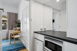 uma cozinha com armários brancos e um balcão preto em Benson House & Benson Lodge em Benalla