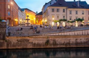 um grupo de pessoas sentadas nas escadas perto de um rio em Viva Rooms em Ljubljana