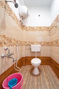 a bathroom with a toilet and a pink bucket at Pavisha Farm House Swimming Pool in Pondicherry