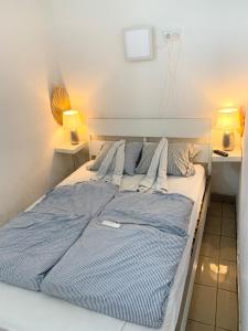 1 cama con almohadas azules y blancas y 2 lámparas en Plum13, en Szolnok