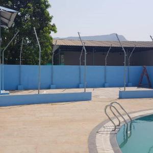 an empty swimming pool in front of a blue wall at Sentosa Farms in Chinchavli
