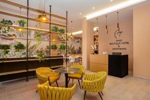 un restaurante con mesa, sillas y plantas en Toto Boutique Hotel & Apartments en Vlorë