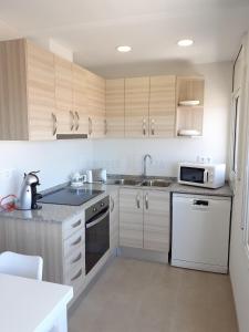 eine Küche mit weißen Geräten und Holzschränken in der Unterkunft Apartamentos Dins Mar Apto. 8 in Torredembarra + 12 Fotos