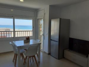 eine Küche mit einem Kühlschrank sowie einem Tisch und Stühlen in der Unterkunft Apartamentos Dins Mar Apto. 8 in Torredembarra