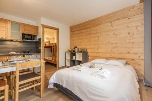 Cet appartement comprend une chambre avec un grand lit blanc et une cuisine. dans l'établissement Chamonix Sud - Grepon 102 - Happy Rentals, à Chamonix-Mont-Blanc