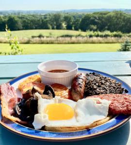 a plate of breakfast food with eggs and sausage at Jacquie's B&B -Dumfries-Room with a view - hot tub in Dumfries