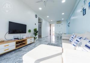 uma sala de estar com um sofá e uma televisão de ecrã plano em Port Dickson 10Pax 3BR Glory Beach Resort Seaview em Porto Dickson