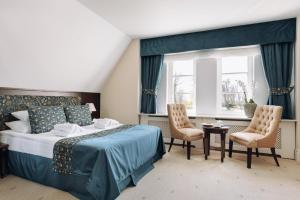 a bedroom with a bed and two chairs and a window at Hotel Pałac Romantyczny in Turzno