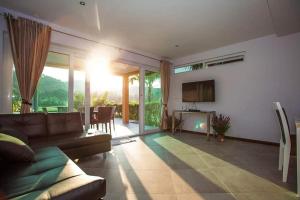 a living room with a couch and a television at Blue Cove Pool Villa in Trat