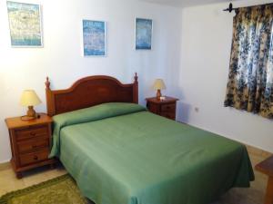 um quarto com uma cama verde e duas mesas de cabeceira em El Capistrano em Nerja