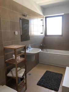 La salle de bains est pourvue d'un lavabo, d'une baignoire et de toilettes. dans l'établissement Skyline Snagov Lake Apartments - Club Lac Snagov, à Turbaţi