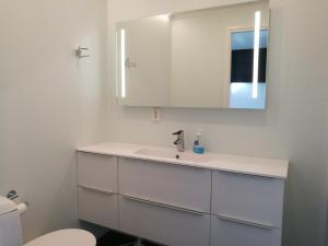 Un baño blanco con lavabo y espejo. en Villa Repolainen, en Syöte 24 fotos más