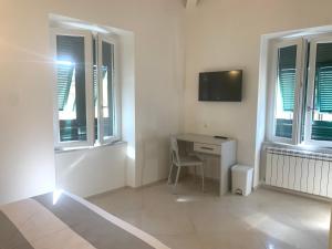 um quarto branco com uma secretária e 2 janelas em Affittacamere Stella di Mare em Levanto
