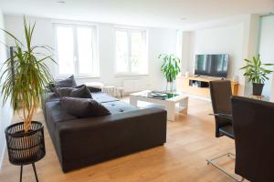 a living room with a black couch and some plants at The City Suite - Luxuswohnung in Kempten