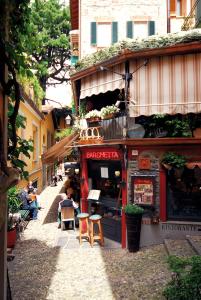 a street with people sitting outside of a building at Locanda Barchetta - Room Rental in Bellagio